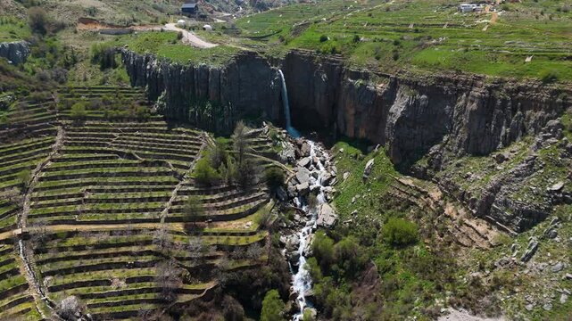 Aerial footage of a waterfall in Faraya with green fields and natural rocky surroundings