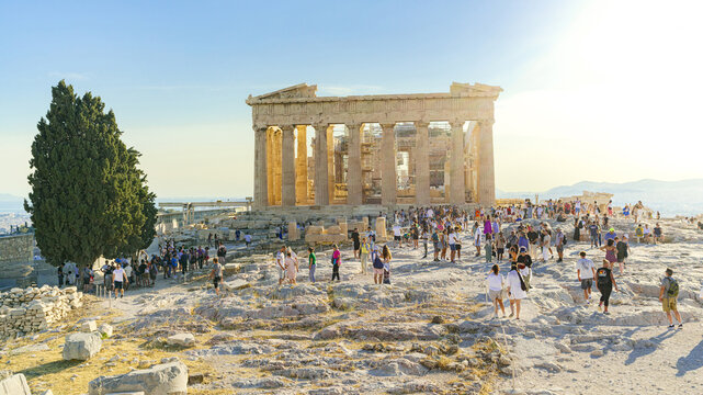 View of the majestic Parthenon bathed in golden sunlight, with crowds of people exploring its ancient grandeur, Athens, Central Athens Regional Unit, Greece.