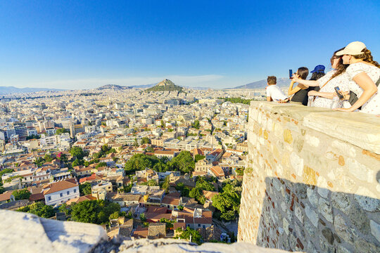 View of the sprawling cityscape stretching towards the iconic Lycabettus Hill under a clear sky, captured from a stone vantage point, Athens, Central Athens Regional Unit, Greece.