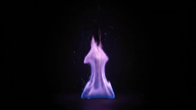 Mesmerizing blue and violet flame dancing in the darkness with sparks floating gently around