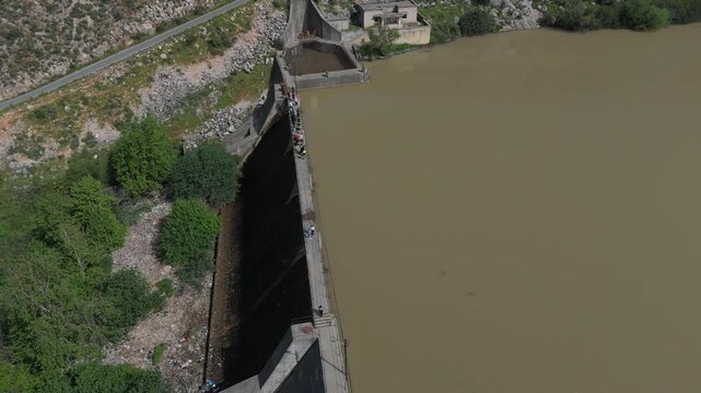 High angle drone shot of Oyoun El Samak water reservoir in Lebanon with people walking across the dam