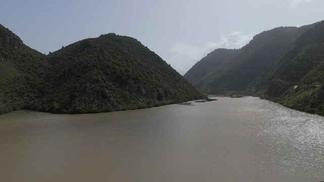 Cinematic aerial view of Oyoun El Samak dam showing reservoir water, bridge structure and natural surroundings
