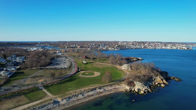 Stage Fort Park with its baseball field and coastline on sunny day in Gloucester, Massachusetts, USA. Aerial drone ascending, copy space