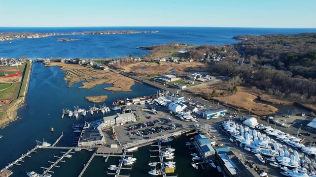 Aerial view of Gloucester, Massachusetts harbor port with marina docks, boats, blue water and scenic coastline. Classic New England maritime atmosphere on bright sunny day. Wide shot.