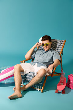 Stylish young man relaxing in summer attire by the poolside with colorful accessories