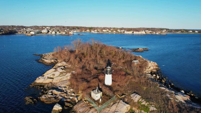 Annisquam Harbor Lighthouse on small island with town in background in Gloucester, Massachusetts. Aerial forward, copy space