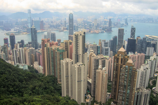View of towering skyscrapers piercing the sky above green hills, reflecting the urban pulse of a vibrant metropolis, Hong Kong, Hong Kong, China.