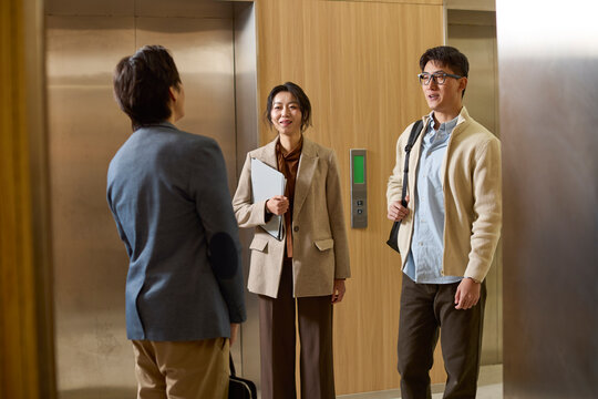 Business associates conversing while waiting for the elevator
