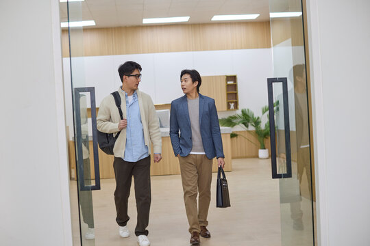Two businessmen talking while walking in an office