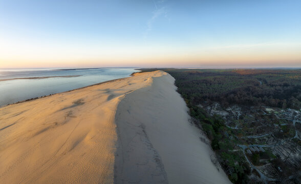Aerial view of the sublime Dune du Pilat, a symphony of golden sands meeting the deep green forest and the tranquil blue ocean, La Teste de Buch, Nouvelle-Aquitaine, France.