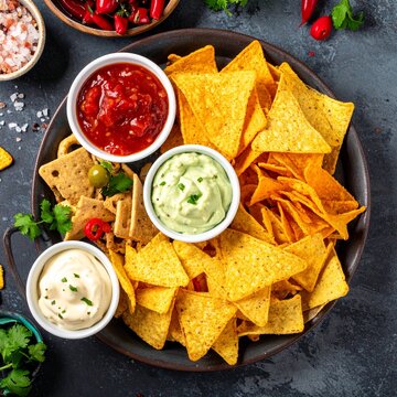 A plate of tortilla chips with salsa guacamole and queso dip.