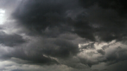 Fototapeta premium Dark thunderstorm clouds rainny season. Meteorology danger windstorm disasters climate. Banner Dramatic dark storm clouds black sky background. Dark thunderstorm clouds rainny atmosphere.