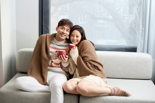A young couple snuggling closely on the sofa