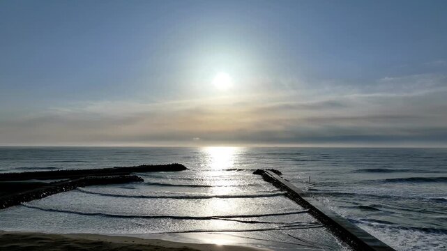 Aerial sunrise glow on ocean surface with light path leading to horizon, Tomioka Fukushima