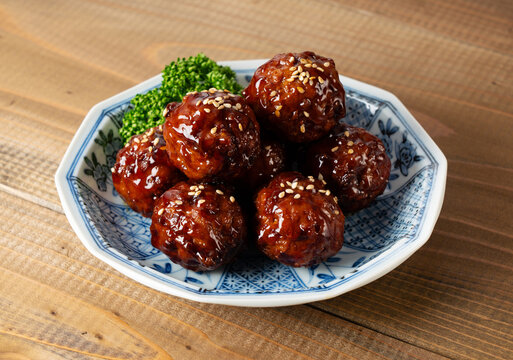 Delicious glazed meatballs with sweet and sour sauce, sesame seeds and parsley on a ceramic plate