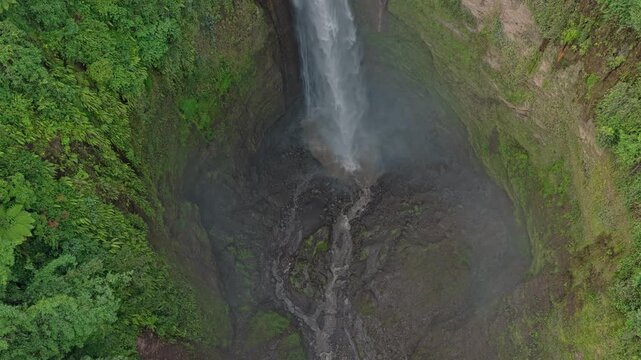 Drone flying up the kabut pelangi waterfall in indonesia