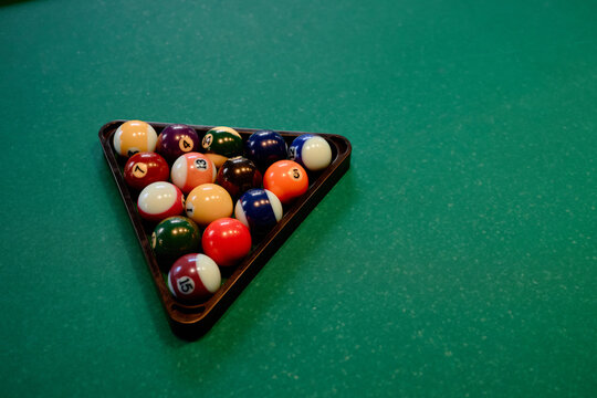 Close up of billiard balls resting in triangle rack on pool table, representing leisure gaming and competition. Suitable for sports bar promotion, entertainment ads, tournament marketing

