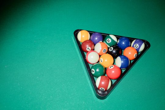 Overhead shot of billiard balls resting in rack on pool table, showing game setup and leisure competition concept. Useful for sports club promotion, entertainment ads, or recreation content
