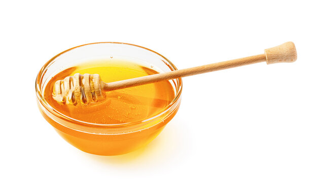 Golden honey in glass bowl with wooden dipper