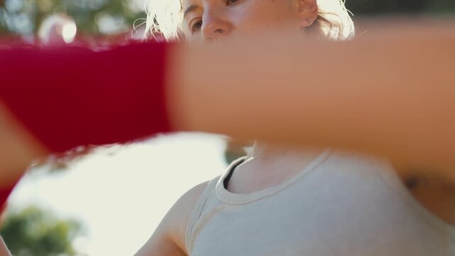 Woman boxer wrapping hands for training outdoors