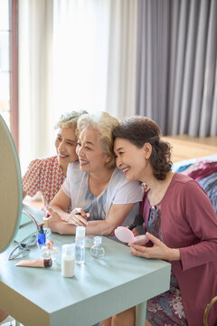 Senior female friends try out new cosmetics and beauty products