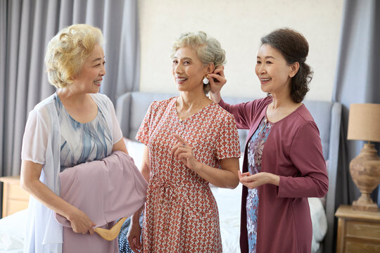 Senior female friends trying out new dresses and new earrings