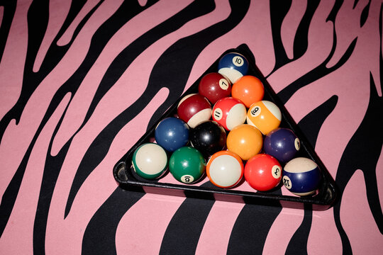Overhead shot of billiard balls resting in rack on zebra pattern surface, presenting retro leisure concept. Useful for gaming promotion, bar advertising, entertainment branding
