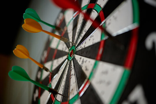 Close up of darts hitting bullseye on dartboard, showing accuracy, goal achievement, winning strategy, performance metrics. Ideal for business targets, success planning, KPI concepts

