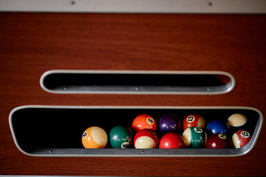 Close up of billiard balls resting in pool table return tray, showing leisure gaming equipment and recreation concept. Suitable for sports club promotion, bar marketing, or entertainment ads
