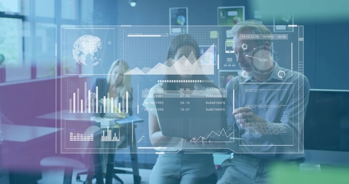 Reviewing two coworkers in business casual working on laptop in open-plan office with HUD charts