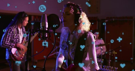 Fototapeta premium Singing singer wearing headphones holding guitar in dim studio with mic, pop filter, floating icons