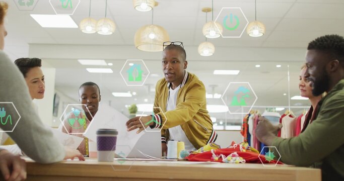 Leading designer wearing yellow jacket leaning across table in studio, showing fabric swatches