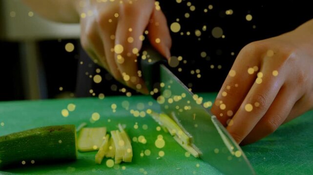 Left hand holding chunk, knife slicing strips, right hand stacking slices under gold bokeh for meal