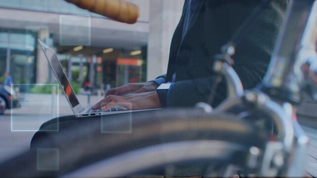 Low-angle opening via bike wheel front showing man typing laptop squares marking keys for tech work