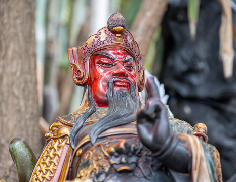 Aberdeen, Hong Kong, China : close up of Guan Yu Chinese warrior deity statue with red face and traditional armor in coastal shrine setting