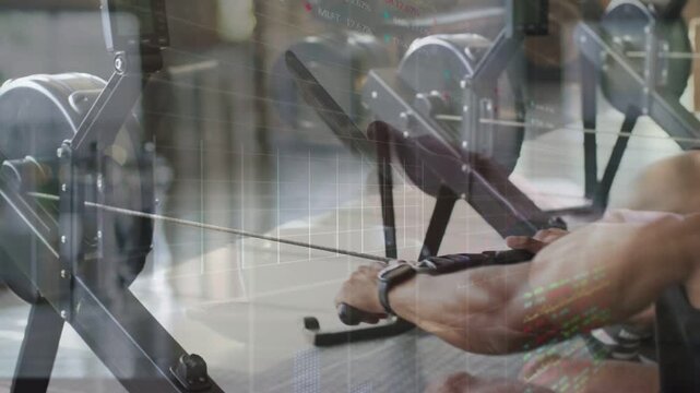 Man initiating leg drive on rower, pulling handle while flywheel turning, peer seen right training