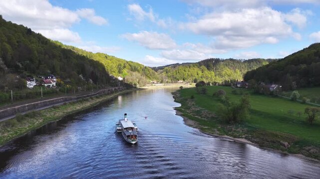 Aerial view of a historic paddle steamer cruising up the Elbe River through the picturesque Elbe Valley in Saxon Switzerland.