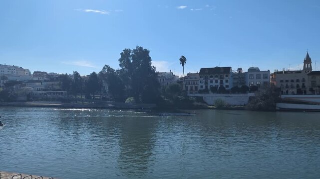 Sevilla Spain Scenic waterfront view showcasing serene river and urban countryside with buildings palm trees reflecting clear sky and tranquil waters in a peaceful setting. Generative AI