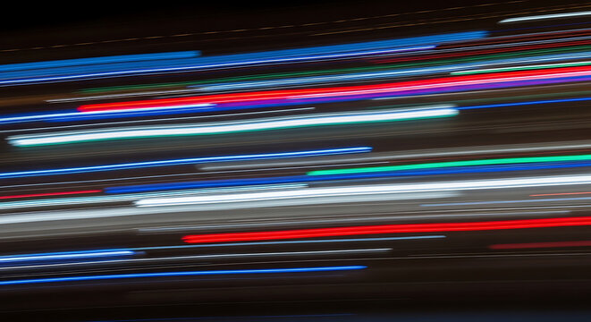 A close up of a computer keyboard and mouse over a colorful red and green abstract background with bright light lines and a blurred motion texture for a web business backdrop