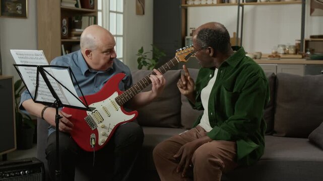 Front view shot of middle aged music teacher teaching adult Black man and handing him electric guitar during lesson Ideal for beginner onboarding materials