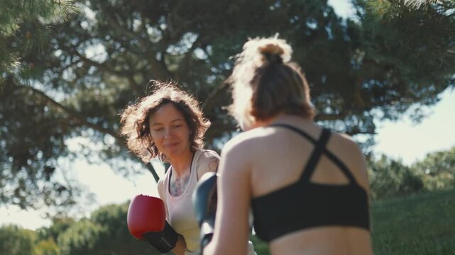 Two women boxers sparring together outdoors