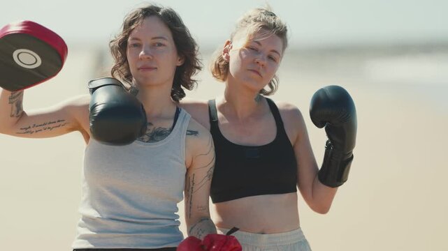Tattooed female boxers posing together on a sunny beach