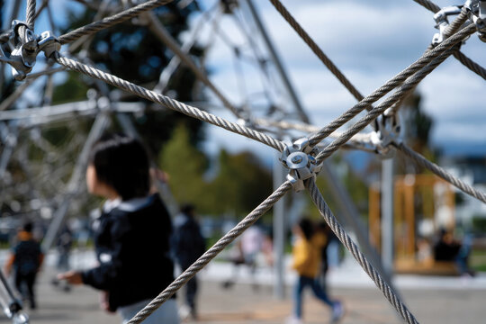 The image showcases an exciting playground structure featuring interwoven ropes, capturing children joyfully exploring the climbing apparatus in bright daylight.