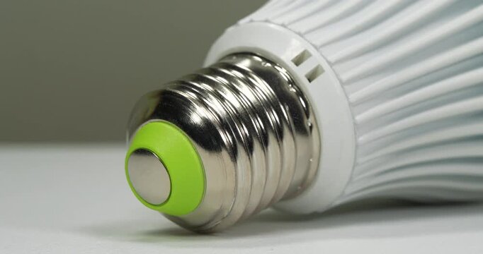 White energy saving LED lamp with E27 base on grey background, close-up zoom-out video