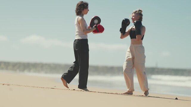 Women practicing boxing workout on a sandy beach