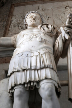 Statua monumentale di imperatore romano in armatura classica, scultura in marmo bianco con dettagli della lorica e mantello, simbolo dell'Impero Romano e del potere antico