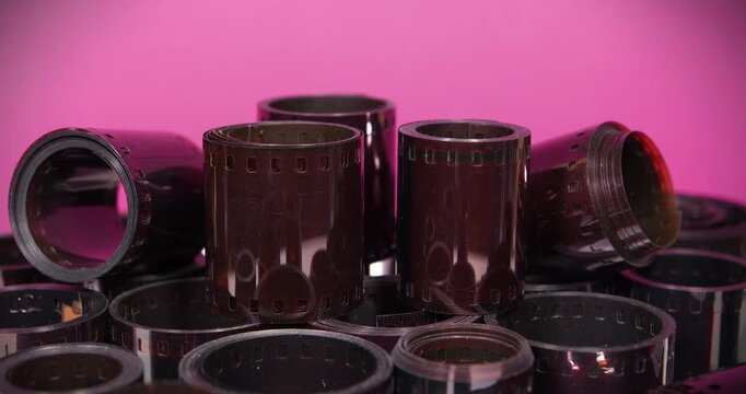 Old photographic films rotates on pink background. Vintage film rolls for classic photography. Old camera film for retro photo shoots. Developed retro film rolls from analog cameras