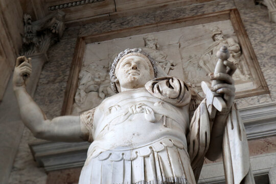 Statua monumentale di imperatore romano in armatura classica, scultura in marmo bianco con dettagli della lorica e mantello, simbolo dell'Impero Romano e del potere antico
