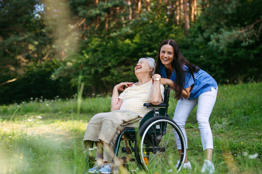 Home nurse taking care of elderly woman in wheelchair.