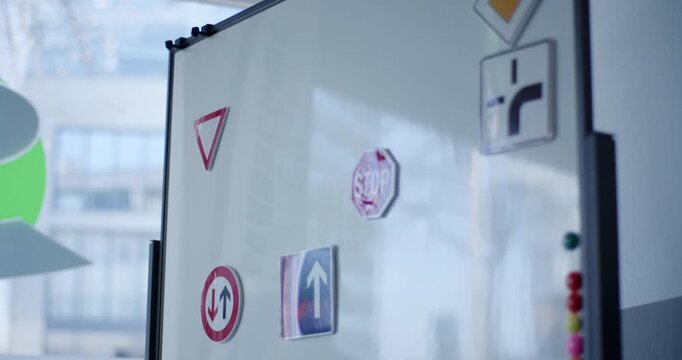 Selection of European road sign miniatures with magnets attached to white board in driving school classroom